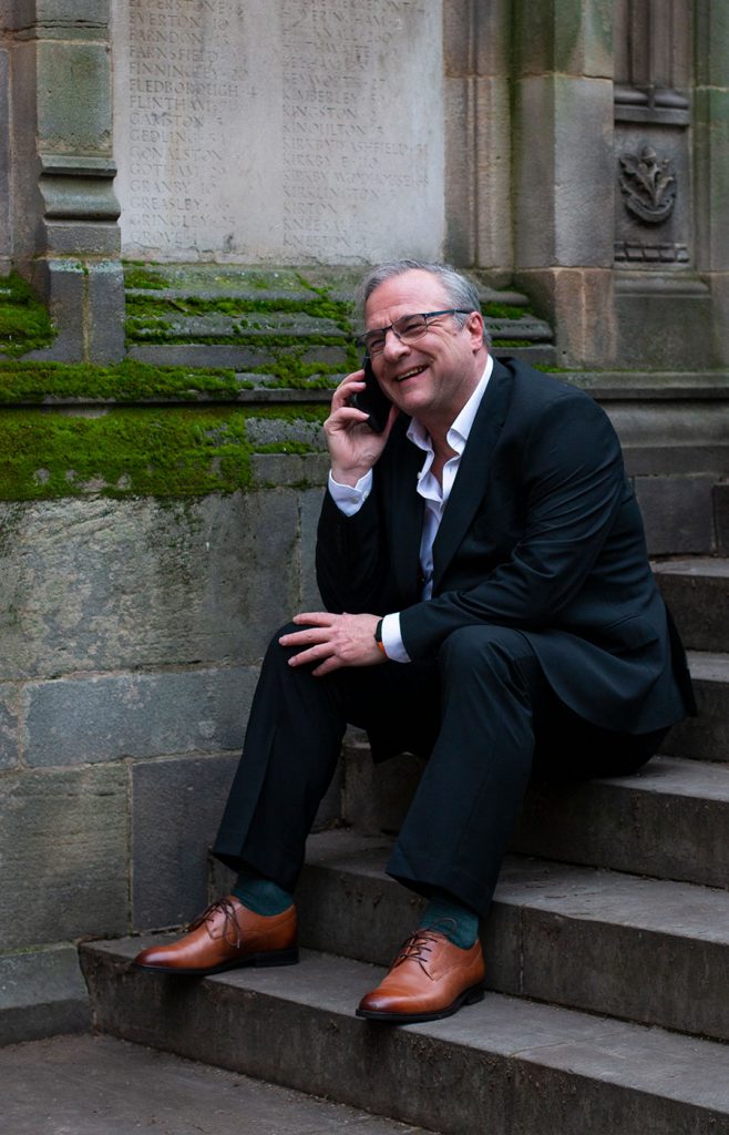 Theo Pangraz, Dual-Qualified Senior Barrister, sitting having a phone call sitting on steps